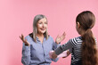 © New Africa - Little girl greeting her grandmother with gift on pink background
