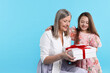 © New Africa - Little girl greeting her grandmother with gift on light blue background, space for text