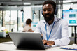 © DC Studio - Black male office worker uses laptop at desk, enjoying music and checking online updates of company. Businessman with headphones works on digital device, finalizing budget funds report.