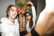 © Studio Marmellata - Three young friends wearing colorful sunglasses laugh and pose for a photo at a vibrant party, capturing a moment of joy and connection.