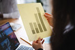 © Studio Marmellata - A person reviews a bar chart showing data from April to July, with a laptop open on the table.