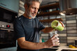© Davor - Mature man pouring green smoothie in home kitchen