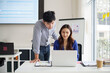 © matinee - Business colleagues collaborating on financial reports while reviewing data on laptop in modern office. Teamwork and strategy development concept.