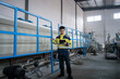 © zhu difeng - Factory worker holding tablet while inspecting industrial equipment in workshop