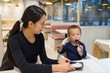 © leungchopan - Mother feeding baby food at restaurant table