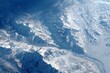 © Art Jabz - Aerial view of snow-covered mountains with glaciers and cloud formations, showcasing a vast, icy landscape