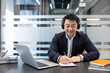 © Liubomir - Asian businessman wearing headphones working in modern office