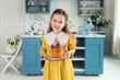 © stock_studio - Young cute girl with easter cake in hands. Smile child holding easter pastries, celebrating easter and spring. Happy little girl holding a baking with baked cake in her hands on festive house kitchen