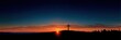© Iryna - Sunset cross silhouette horizon prayer over rolling hill with dramatic orange sky and sunburst on the ridge at dusk, peaceful spiritual landscape scene