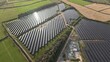 © AmazingAerialAgency - Aerial view of vast solar panels reflecting the sky amidst the vibrant green fields of Halloughton Solar Array, Halloughton, United Kingdom.