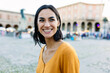 © Xavier Lorenzo - Smiling portrait of happy young pretty woman standing at city street. Outside portrait of joyful beautiful girl over urban background.
