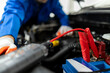 © zphoto83 - Mechanic using jumper cable clamp on car battery during service