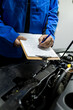 © zphoto83 - Mechanic writing vehicle service report over open engine compartment