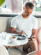 © Aboltin - Man working on tablet in cafe after breakfast, managing tasks and checking content. Remote work, productivity and modern business lifestyle concept