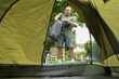 © Wosunan - View from inside a tent showing a mature man preparing camping gear outdoors