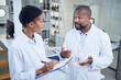 © peopleimages.com - Scientist, man and woman with clipboard in lab, writing or planning for medical research with mentor. Clinic, collaboration and black people with info for study, healthcare and discussion with notes