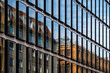 © yaqui_villegas - Reflective urban glass facade with linear rhythm creating modern corporate architecture pattern for business real estate concepts and abstract background design