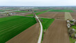 © AmazingAerialAgency - Aerial view of a patchwork of verdant fields and earthy tones intersected by a solitary road under a vast sky, Sremska Mitrovica, Vojvodina, Serbia.