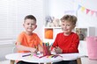 © New Africa - Cute little boys drawing with felt tip pens at white table indoors