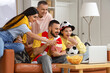© Pixel-Shot - Soccer fans with snacks watching game on laptop at home
