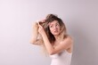 © New Africa - Unhappy woman trying to brush her tangled hair on light grey background