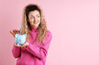 © New Africa - Happy woman putting banknote into piggy bank on pink background, space for text