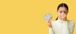 © Pixel-Shot - Young Asian woman with paper brain suffering from headache on yellow background with space for text