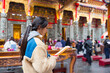 © leungchopan - Woman performing prayer ritual inside traditional temple
