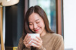 © Farknot Architect - Portrait image of a woman with closed eyes holding and drinking hot coffee