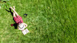 © Iuliia Sokolovska - Young woman reading book in park in summer, girl relaxing outdoors on grass with book and headphones, analog lifestyle and digital detox trend, aerial drone view from above