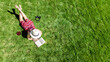 © Iuliia Sokolovska - Young woman reading book in park in summer, girl relaxing outdoors on grass with book and headphones, analog lifestyle and digital detox trend, aerial drone view from above
