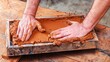 © comicsans - A brick factory worker pressing wet clay into a rectangular steel mold frame.