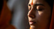 © Kala - A young woman with eyes closed, wearing an orange garment and a red bindi, in a moment of quiet reflection or prayer