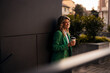 © Jelena - Smiling businesswoman holding coffee cup outdoors enjoying break
