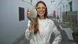 © Krakenimages.com - Woman scientist holding a pump bottle in hand on a narrow street in a white labcoat and glasses; health safety confidence.
