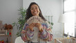 © Krakenimages.com - Woman holding a fan of cash with hands visible in a baby room inside a residential building; financial joy.