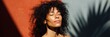 © Andrii Zastrozhnov - African female young sunlit portrait with curly hair eyes closed palm shadow on red and gray wall cinematic light