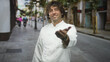 © Krakenimages.com - Man chef in white uniform smiles, tilts head slightly and extends hand in a welcoming gesture on a busy city street; welcoming hospitality.