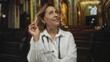 © Krakenimages.com - Woman doctor wearing white coat and stethoscope turns her gaze upward and points finger to head in building; contemplation.