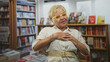 © Krakenimages.com - Woman with hands on chest and yellow glasses in a bookstore building, wearing beige belt and bracelets, expressing a thankful gesture; gratitude.