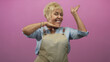 © Krakenimages.com - Senior hispanic woman in apron frames face with smiling hands near cheek and chin in studio; joy confidence.