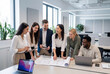 © Meow Creations - Diverse group of colleagues reviewing blueprint in modern office