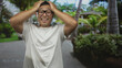 © Krakenimages.com - Man wearing glasses and a white tee holds head with both hands and smiles with open mouth in forest; surprise.