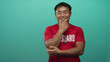 © Krakenimages.com - Young chinese lifeguard man in red shirt with lifeguard print and whistle holds chin in studio with green wall; contemplation.