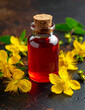 © Bediha Duru Öksüz - St. John’s Wort oil in glass bottle with Hypericum perforatum flowers. Red St. John’s Wort oil in a glass bottle surrounded by Hypericum perforatum flowers on a dark background. Natural herbal remedy.