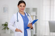 © New Africa - Portrait of doctor in medical uniform with stethoscope and clipboard in clinic. Space for text