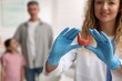 © New Africa - Smiling endocrinologist in protective gloves with model of thyroid gland and patients indoors, selective focus