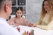 © New Africa - Little girl and her mother having appointment with endocrinologist at white desk in clinic, closeup