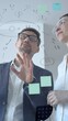 © volha_r - Business professionals brainstorming analyzing data and developing new strategies on a transparent whiteboard with handwritten diagrams and digital tablet