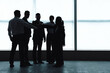 © Pixel-Shot - Silhouettes of business people putting hands together near window in office
